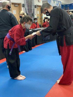 Respecting his Master when receiving his 3Purple belt.