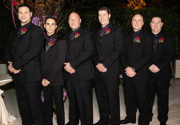 Black on black tuxes with black shimmer vest and purple ties/bow tie.