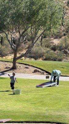 Five year-old and a friend playing corn hole while we wait for our orders