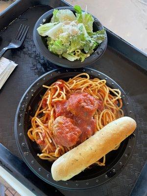 Spaghetti and meatballs with a garlic breadstick and caesar salad.