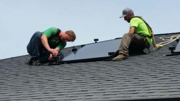 Crew hard at work installing black on black panels on rooftop.