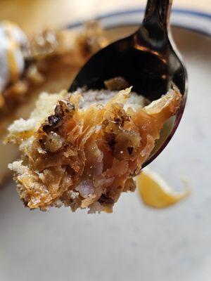 A spoon with the Baklava Cheesecake with walnuts and whipped cream and caramel sauce.