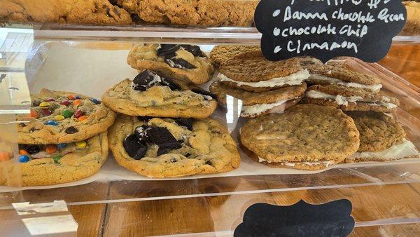 Arrangement of giant cookies M&M cookie,  chocolate chip oreo, and Oatmeal cream cookie.