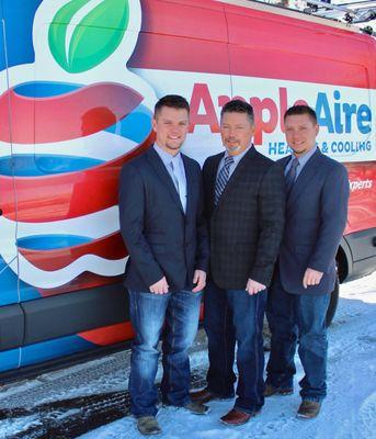 Three members of the Apple Aire Heating & Cooling team standing in front of their company vehicle, which is adorned with the ...