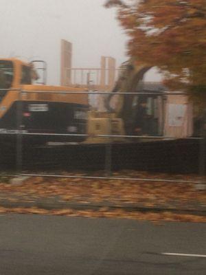 Construction equipment inside fenced compound of where the McDonald's sign is