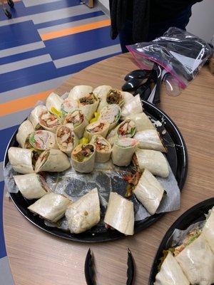 Wrap platter with vege juice saturating the wax paper beneath the sandwiches and the hole of missing wraps.