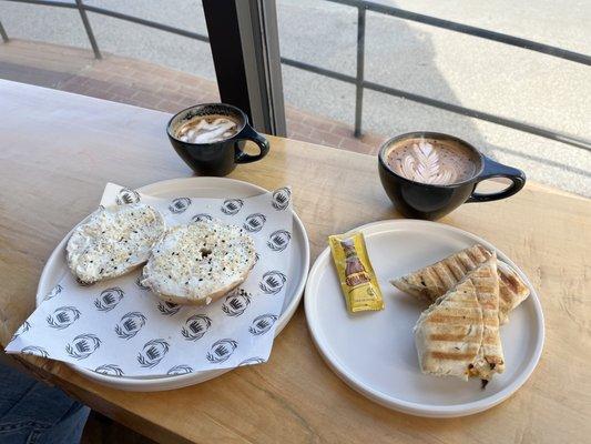 Bagel with cheese, breakfast burrito with a spicy latte and a Neapolitan latte.