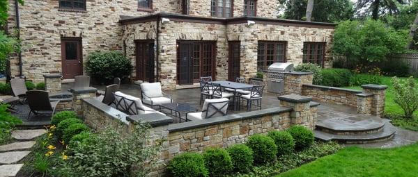 A raised natural stone terrace with sunken fire pit circle.