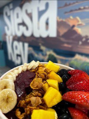 Delicious açaí bowl in front of our hand painted mural from a local artist.