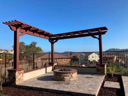 Porcelain tile patio with gas line firepit, lava rock, LED lights, stucco sitting bench wall, veneer stone columns and wood pergola