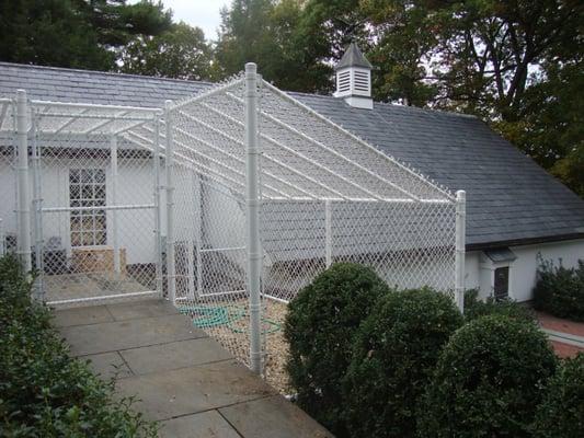 Custom built white vinyl coated chain link dog enclosure with roof for safety.