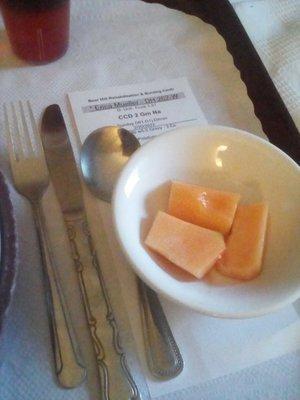 Three bites of fresh cantaloupe, what is claimed to be dinner's half-cup dessert. One of very few examples of fresh fruit on the menu.