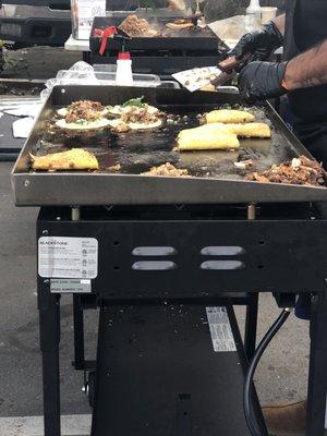 Birria tacos being cooked. Cheese on outside and inside