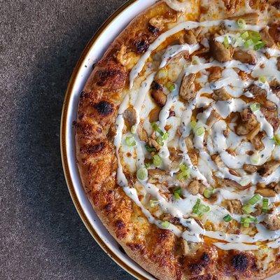 Buffalo Chicken Pizza: New Wing Order Memphis Buffalo sauce topped with chicken, green onions, and house-made ranch drizzle.