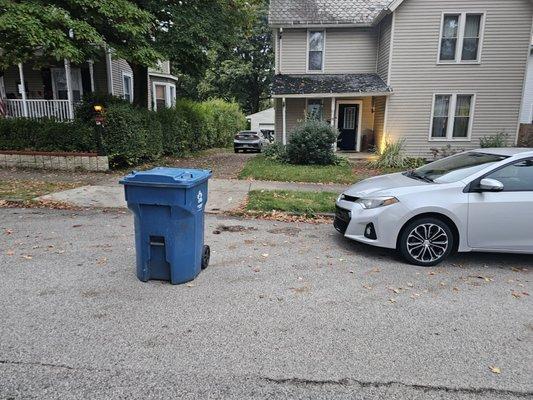 The driver says he can't leave the can on the curb because the car is in the way.