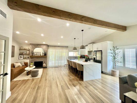 Open floor plan kitchen, ceiling beam, lime wash fireplace and built in cabinet and shelves