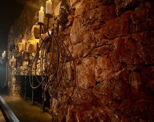 Rock fireplace with cowboy hats in the bar.