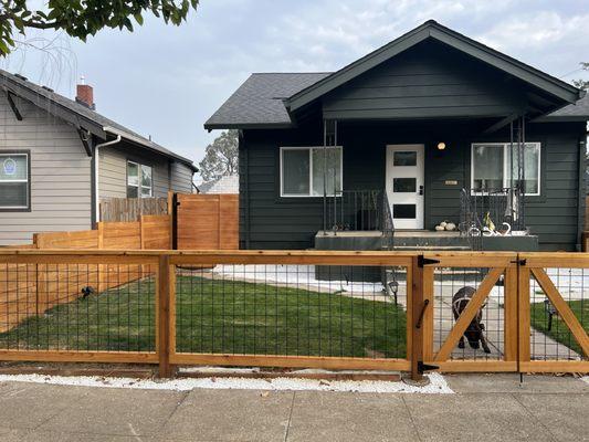 Black hog wire fence wrapped in clear cedar and cedar 2x4 top cap.