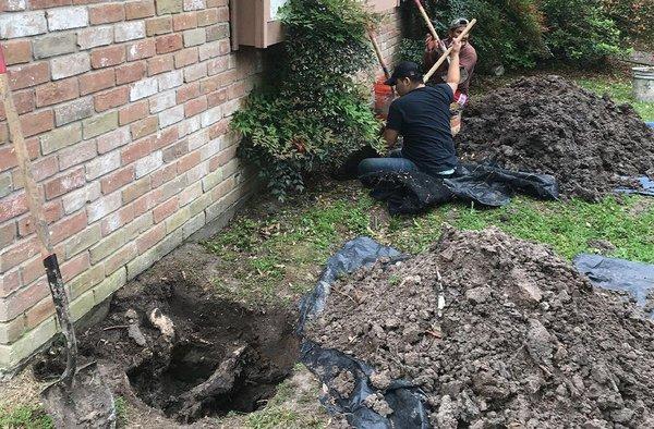 Crew at work digging tunnels for foundation repair through an exterior breakout.