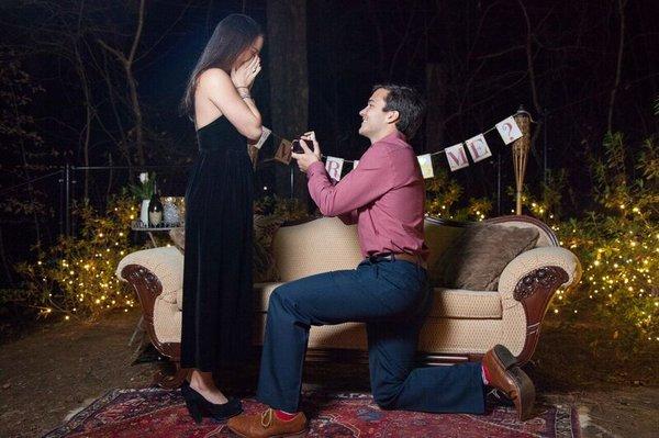 A future groom proposes to his bride surrounded by elegant outdoor party lighting in Atlanta, GA.