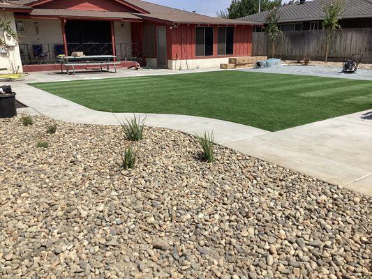 Installed synthetic lawn, concrete, and rock landscaping