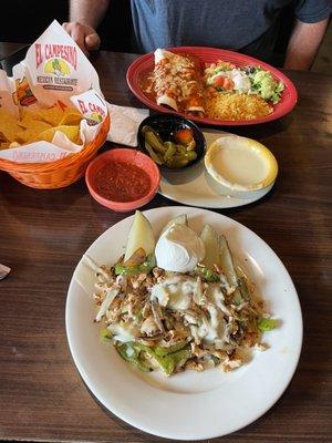 Enchilada plate and potato slices with chicken, bell pepper, and queso.