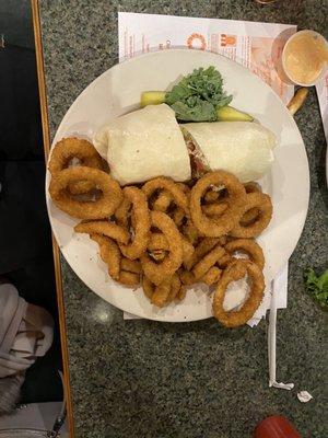 Buffalo chicken finger wrap with onion rings and a pickle