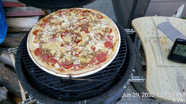 Pizza baked on charcoal Kamado grill.