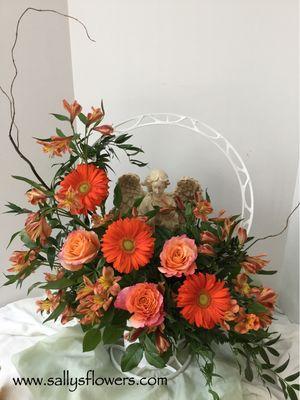 Sympathy arrangement with an angel to bless and comfort family & friends.