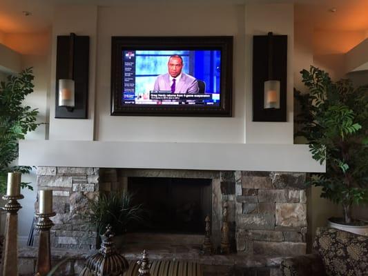 4k Flat Screen TV mounted above fireplace behind art 1