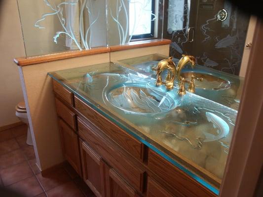 Glass counter top with slumped sink. Etched fish wit h LED lighting