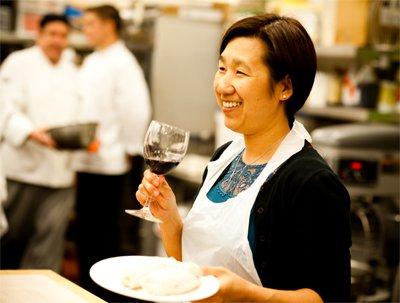 A guest enjoying a glass of wine and sampling her work after a hands-on cooking class.