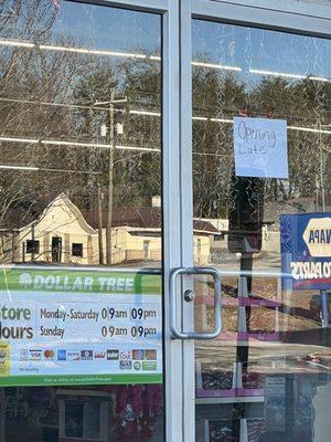 Hand written opening late sign.  Store opens later than "store hours"