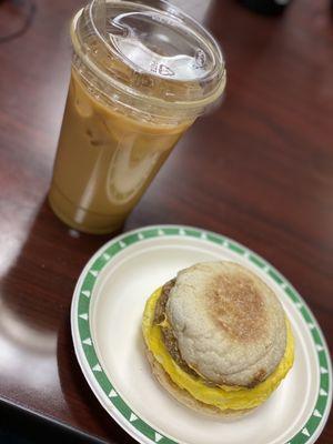 Iced latte with almond milk and egg, cheese, and sausage breakfast sandwich