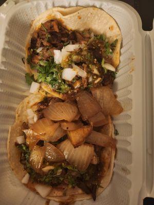 Two al pastor tacos adorned with half-dollar sized chunks of onion