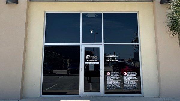 An exterior view of the front entrance to Airrosti Brownsville. Glass doors are visible in the photo, along with a white 2 above the door.