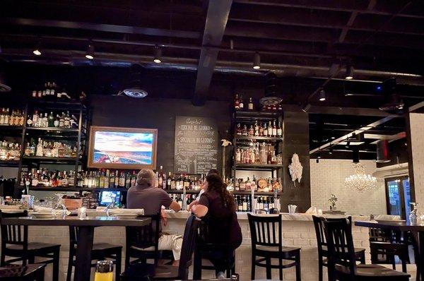 View of the bar from the seating against the wall. Notice the chandelier reflecting in the wall mirror. Stunning.