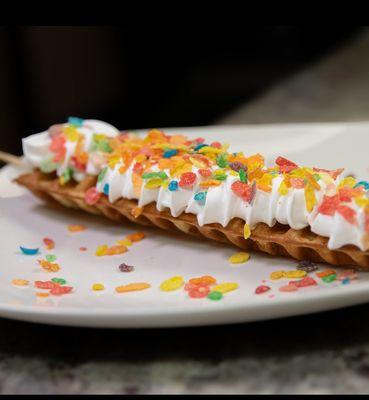 Treat yourself to a whimsical delight with our Waffle-on-a-stick! Coated in colorful Fruity Pebbles and topped with fluffy whipped cream.