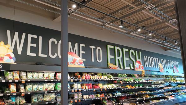 Part of the produce section with a real nice welcome to the store feature on the wall above the package produce