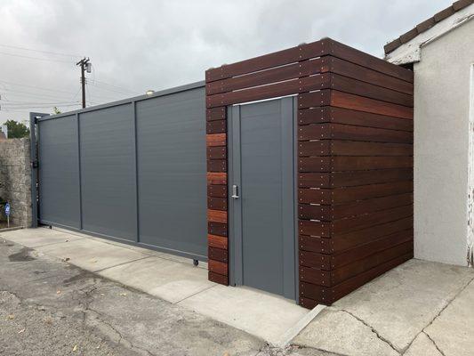 Aluminum rolling gate and pedestrian aluminum door, accented with wood.