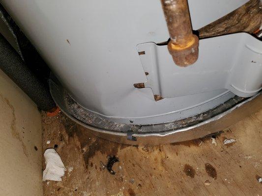 Bent up water heater with the broken brackets laying on floor