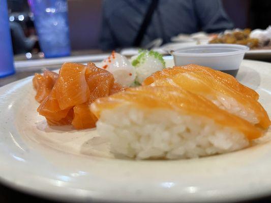 Translucent thin sliced Salmon sushi with poke salmon and ika in the background.