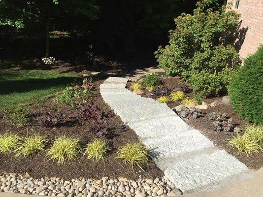 Landscaped slope with stone stairs.