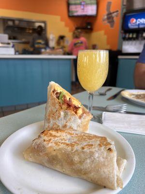 Breakfast burrito with bacon and avocado, and a mimosa