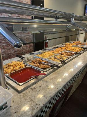 Buffet with sweet and sour chicken, fries, fried donuts