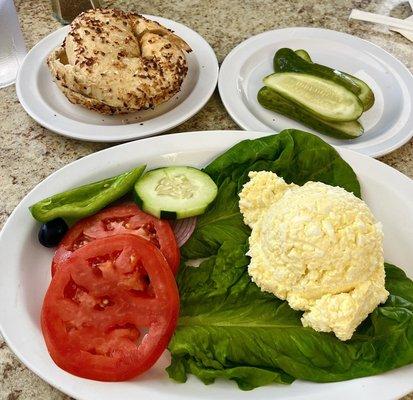 Egg salad platter with toasted onion bagel and a side of pickles