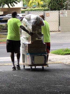 Boxes wrapped on dolly for long transport on rough walkway.