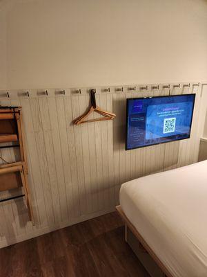 The wall opposite the bed with the series of hooks, adjustable TV screen and fold out seating.