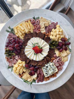 Beautiful charcuterie board filled with local, artisan cheese and meats, delicious crackers and fresh fruit and herbs.