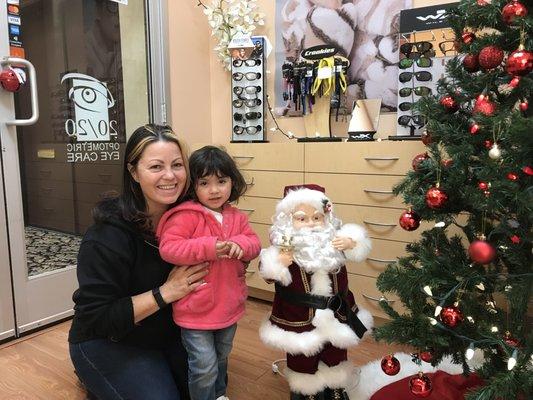 A photo with a young patient and her mom by Santa in the office at 20220 Optometric Eye Care